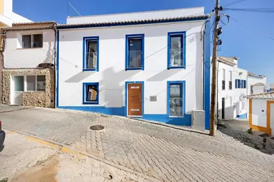 a white and blue house on a cobblestone street at Casinha in Burgau