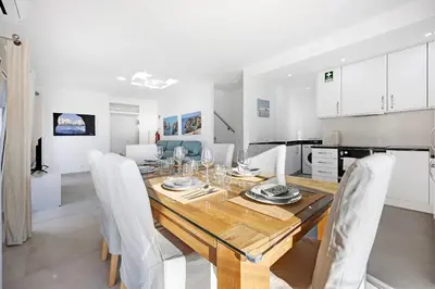 a kitchen and dining room with a wooden table and chairs at Casinha in Burgau