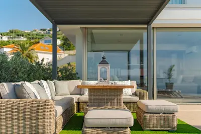 a patio with a couch and a table and chairs at Lê Maison Deluxe Madeira - Where Peace is breathed and Luxury is felt! in Ribeira Brava