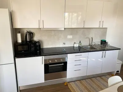 a kitchen with white cabinets and a sink and a microwave at Machico center w/ terrace 5 min beach in Machico