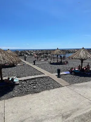 a beach with umbrellas and people laying on the sand at Farinha's Apartment in Ribeira Brava