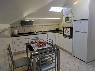 a kitchen with white appliances and a table and chairs at Casa Câmara in Arco da Calheta