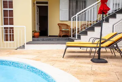 a pool with two yellow chairs next to a house at Villa Margarida in Ponta do Sol