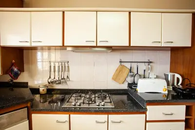 a kitchen with white cabinets and a stove top oven at Villa Margarida in Ponta do Sol