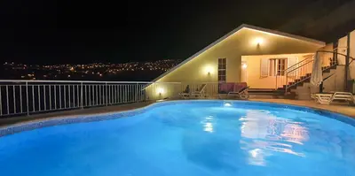 a large blue swimming pool in front of a house at night at Villa Margarida in Ponta do Sol