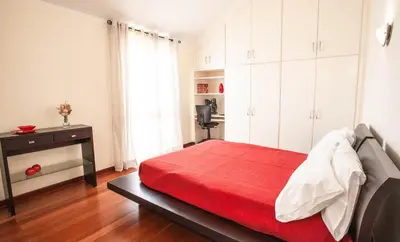 a bedroom with a red bed and white cabinets at Villa Margarida in Ponta do Sol