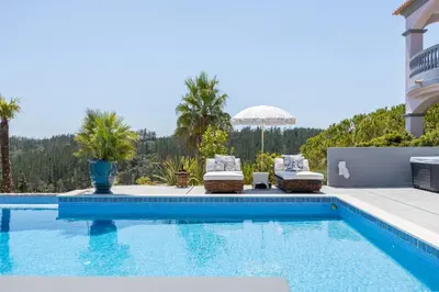 a swimming pool with chairs and a house at Villa Surga, a luxurious and exclusive romantic villa in the Algarve in Budens