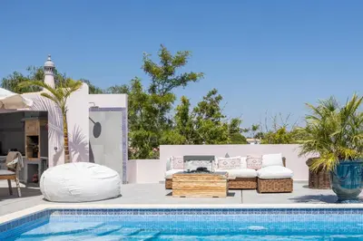a pool with a couch and a table next to a pool at Villa Surga, a luxurious and exclusive romantic villa in the Algarve in Budens