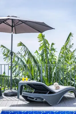 a pool with two lounge chairs and an umbrella at Blue Ocean Villa in Ponta do Sol