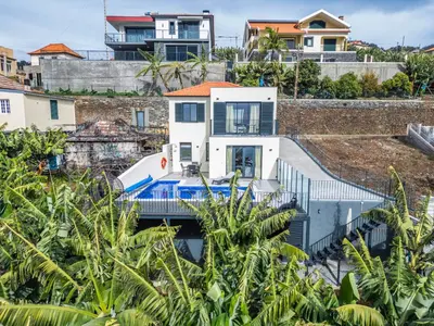 a house with a boat in the water at Blue Ocean Villa in Ponta do Sol