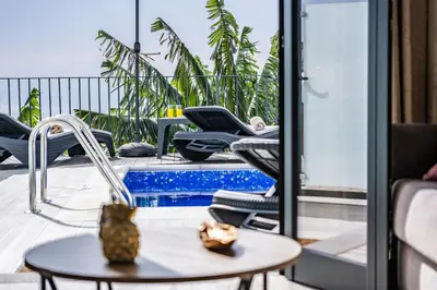 a patio with chairs and a table and a pool at Blue Ocean Villa in Ponta do Sol