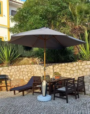 a table and chairs under an umbrella on a patio at Bica da Salema Beach House in Salema