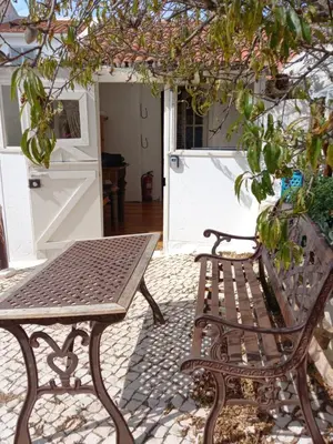 a bench and a table in front of a door at Bica da Salema Beach House in Salema