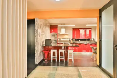 a kitchen with red cabinets and a table with stools at Villa Leonor Cliffside Retreat in Calheta