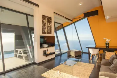 a living room with orange walls and glass windows at Villa Leonor Cliffside Retreat in Calheta