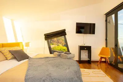 a bedroom with a bed with a tv on the wall at Villa Leonor Cliffside Retreat in Calheta