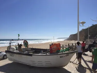 a boat on the beach with people standing around it at Casa Panorama in Salema