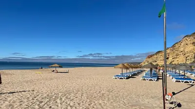 a beach with chairs and umbrellas and the ocean at Casa Panorama in Salema