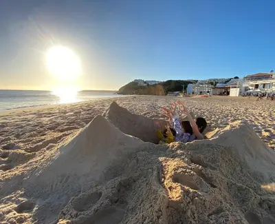 a child laying in a sand castle on the beach at Casa Panorama in Salema