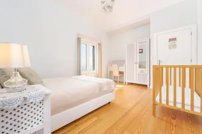 a white bedroom with a bed and a table with a lamp at Casa Pereira – Snooker, Wi-Fi, Bbq, Pool in Relógio do Poiso