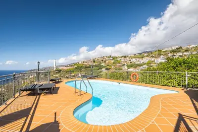 a swimming pool on a balcony with a view of the ocean at Vila Brava Cottage in Ribeira Brava