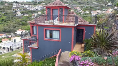 a blue and red house with a balcony at Vila Brava Cottage in Ribeira Brava