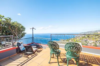 a group of chairs sitting on a balcony overlooking the ocean at Vila Brava Cottage in Ribeira Brava