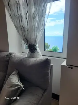 a couch in front of a window with a curtain at Vila Brava Cottage in Ribeira Brava