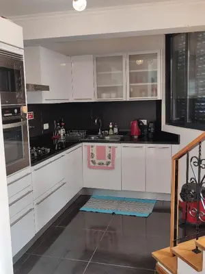a kitchen with white cabinets and a sink at Delfina`s House in Machico