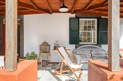 a patio with a chair and a table and a window at Casa Grande da Camélia in São Vicente