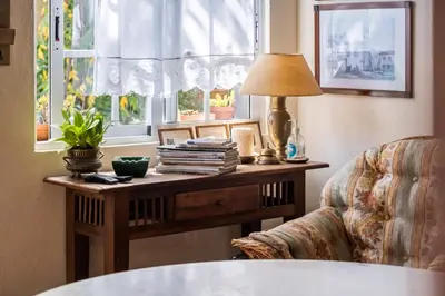 a table with a lamp and a chair next to a window at Casa Grande da Camélia in São Vicente