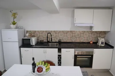 a kitchen with white cabinets and a table with bananas at Fifty's House 2 By Sam Houses in Ribeira Brava