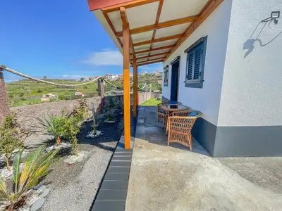 a patio with a table and benches next to a wall at Casa Do Pico in São Vicente