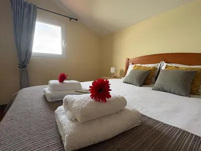 a bed with three towels with red flowers on it at Casa Do Pico in São Vicente