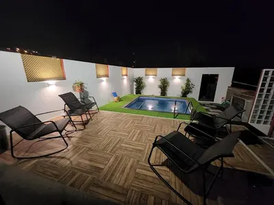 a patio with chairs and a swimming pool at night at Maravilha da Costa in Ponta do Pargo