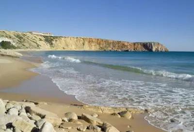 a beach with rocks and the ocean and a cliff at Bonita Moradia c/ Piscina em SAGRES in Sagres