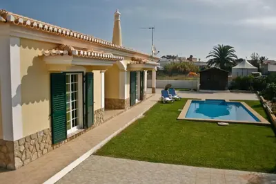 a person sitting in a chair in front of a house at Bonita Moradia c/ Piscina em SAGRES in Sagres