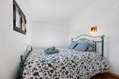 a bedroom with a bed with a black and white comforter at Abrigo do Pescador in Aljezur