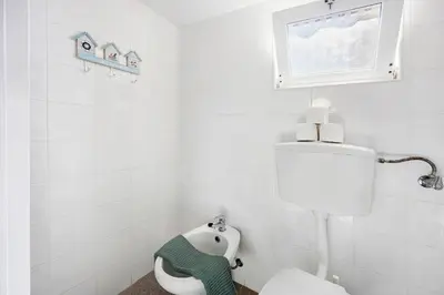 a white bathroom with a toilet and a window at Abrigo do Pescador in Aljezur
