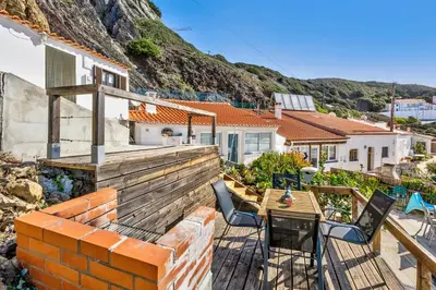 a balcony with a table and chairs and a house at Abrigo do Pescador in Aljezur