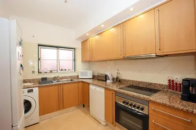 a kitchen with wooden cabinets and a washer and dryer at B95 - Casa Melo Apartment in Praia da Luz in Luz