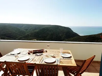 a table with plates and wine glasses on a balcony at Varandas Guest Apartment in Aljezur