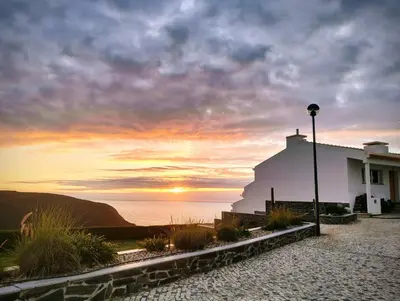 a white building with a sunset in the background at Varandas Guest Apartment in Aljezur
