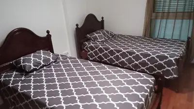 a bedroom with two beds with black and white comforter at Costa Lodges, Funchal or Santa Cruz in Santa Cruz