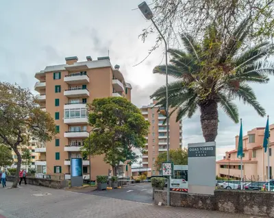 a building with a parking lot in front of the ocean at Duas Torres View Apartment in Funchal