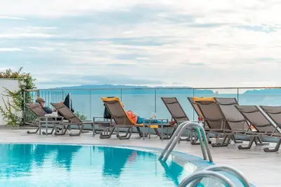 a man sitting in lounge chairs next to a swimming pool at Duas Torres View Apartment in Funchal