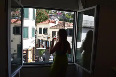 a woman standing in a window taking a picture at Vicente´s LOB ( Lobos Ocean Breeze) in Câmara de Lobos