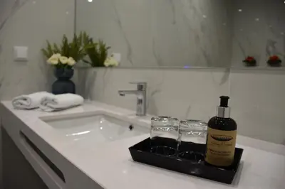 a bottle of wine and two glasses on a bathroom sink at Vicente´s LOB ( Lobos Ocean Breeze) in Câmara de Lobos