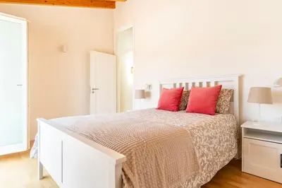 a white bedroom with a large bed with red pillows at Casa Hortas in Vila do Bispo