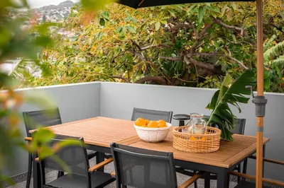 a wooden table with a bowl of oranges on a patio at Achada Sol in Funchal